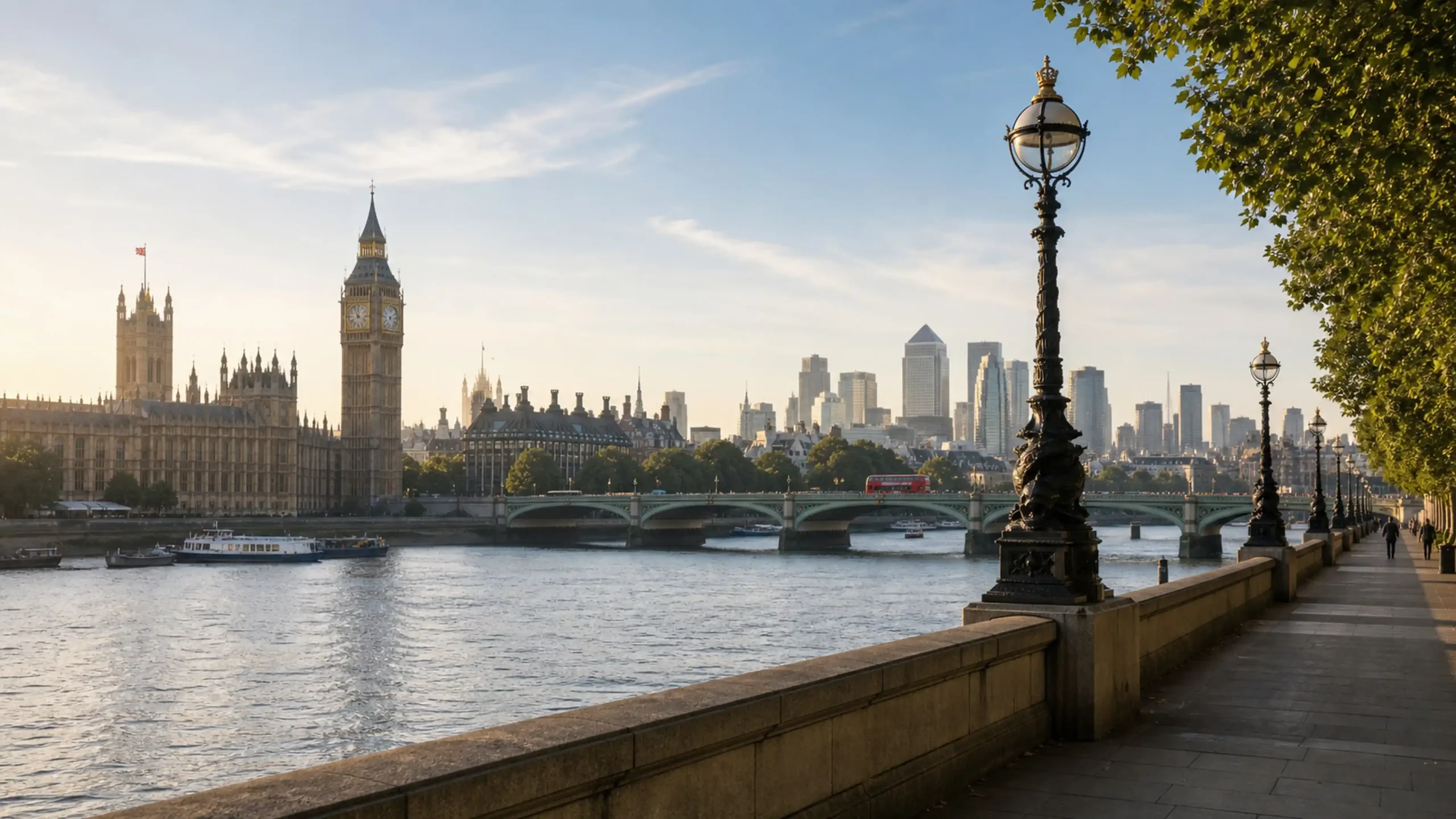 Londra’da Thames Nehri kıyısında tarihi şehir silüeti ve sakin yürüyüş yolu